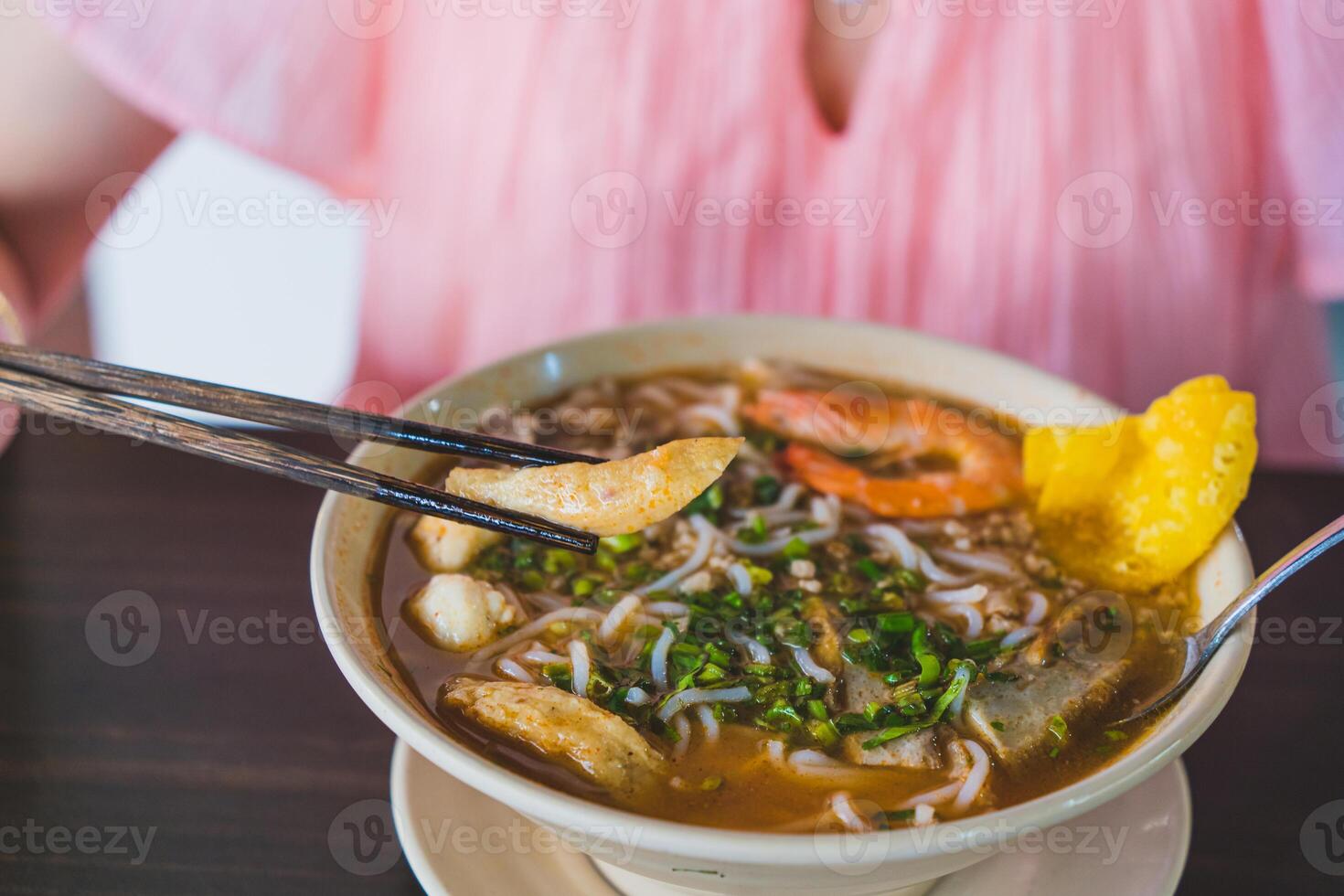 Tom Yum soup - Thai soup with prawns and rice noodles on wooden table in Vietnam photo