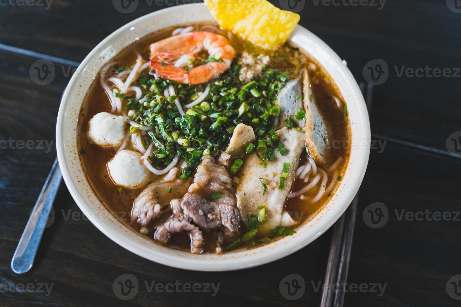 Tom Yum soup - Thai soup with prawns and rice noodles on wooden table in Vietnam photo