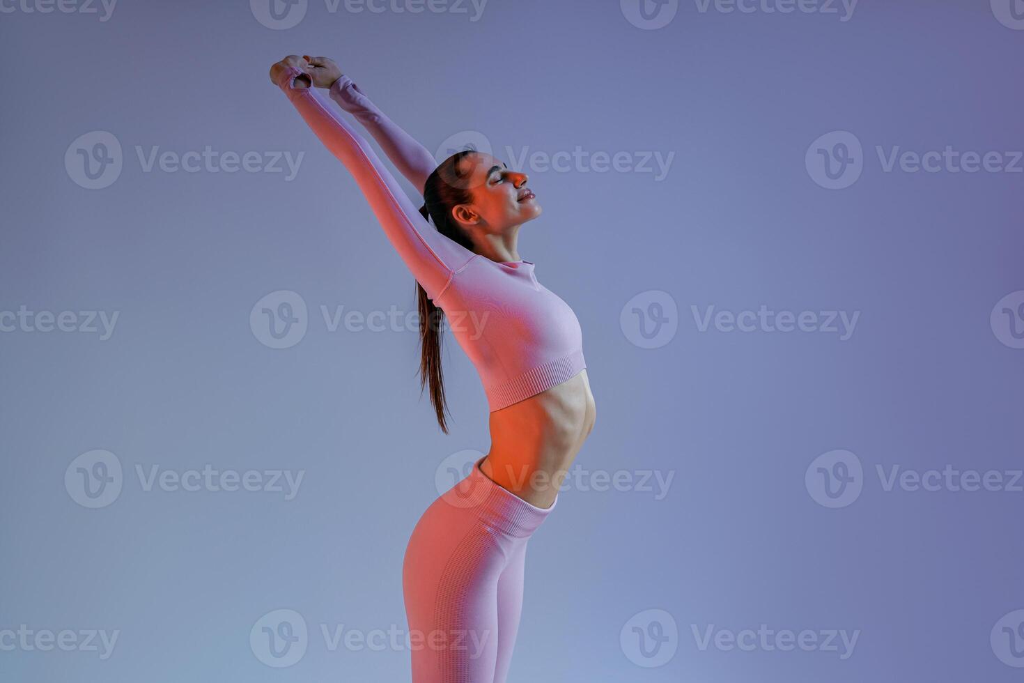 Close up of woman wearing sportswear doing warm-up before training session on studio background photo