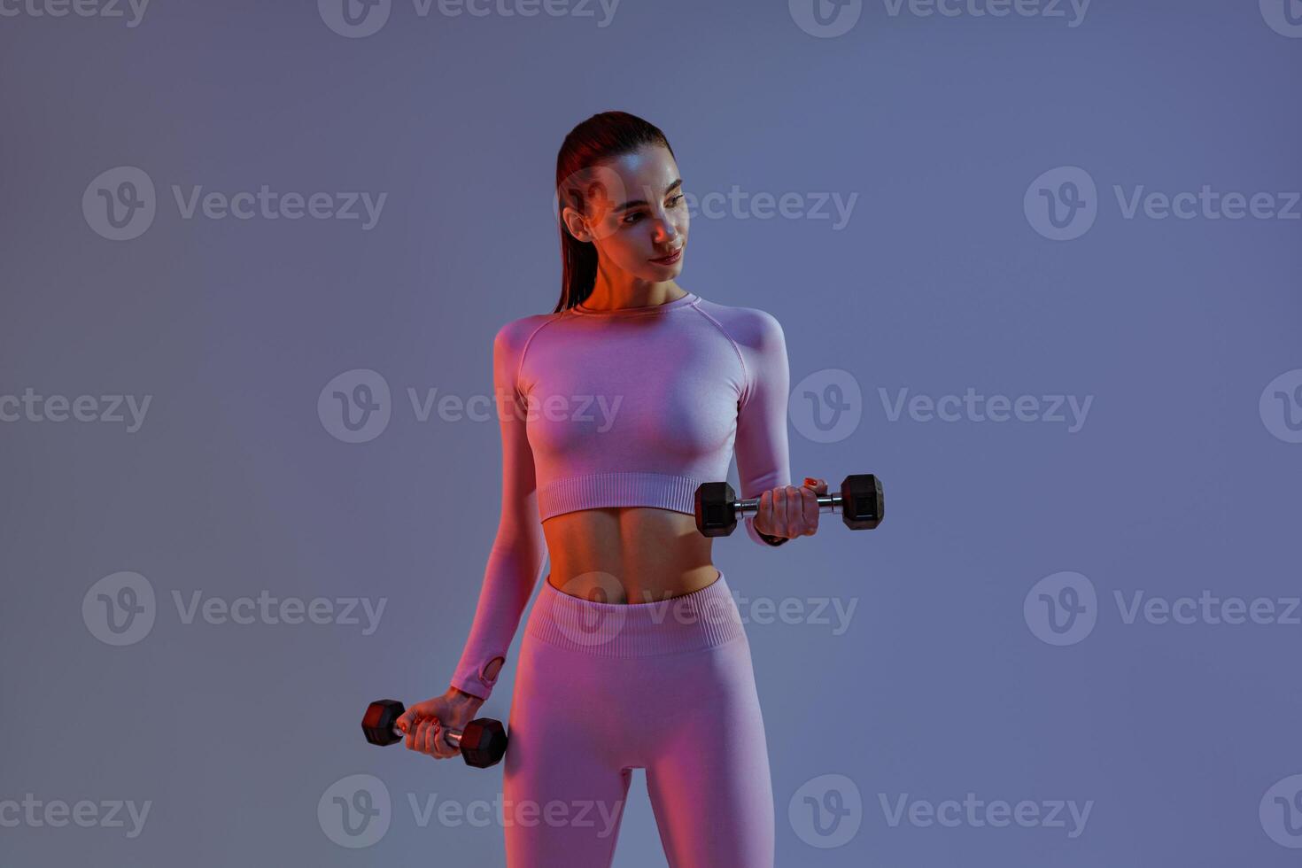 Fitness woman doing exercises with dumbbells on studio background. Strength and motivation photo
