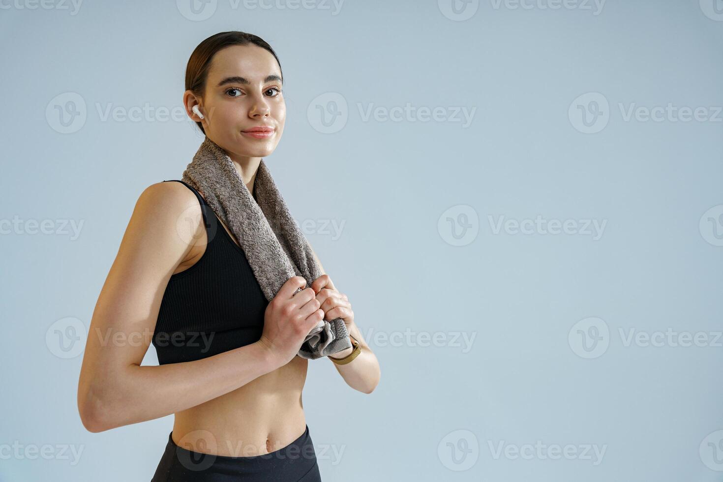 Close up of smiling sporty woman standing with towel around her neck over studio background photo