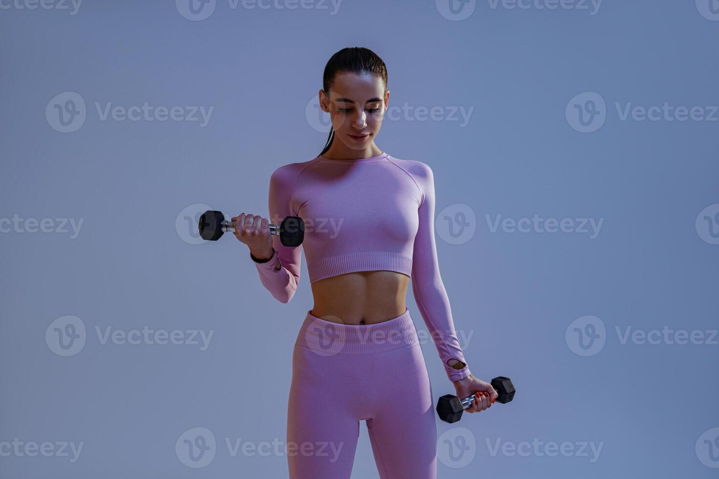 Fitness woman doing exercises with dumbbells on studio background. Strength and motivation photo