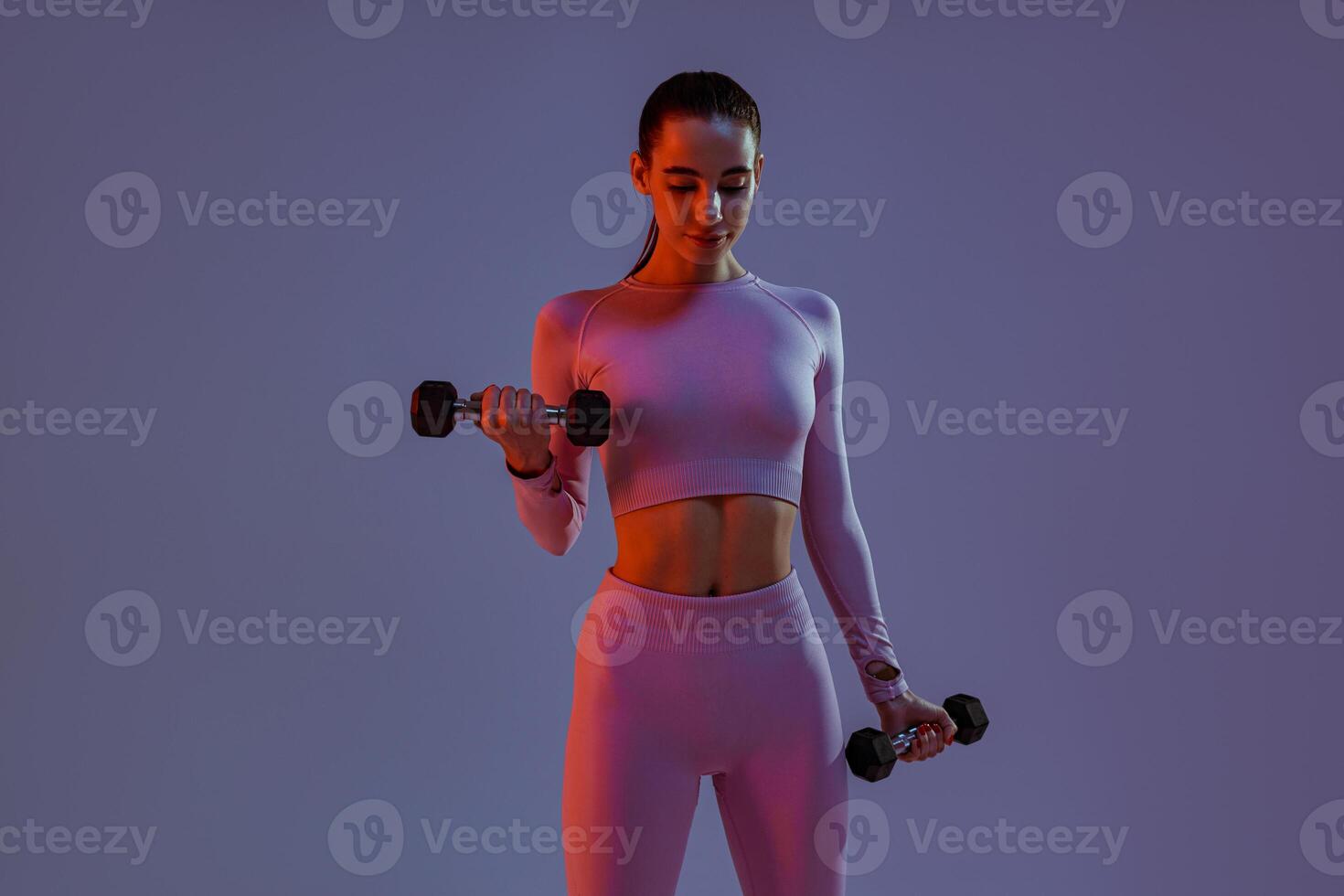 Pretty fitness woman doing exercises with dumbbells on studio background. Strength and motivation photo
