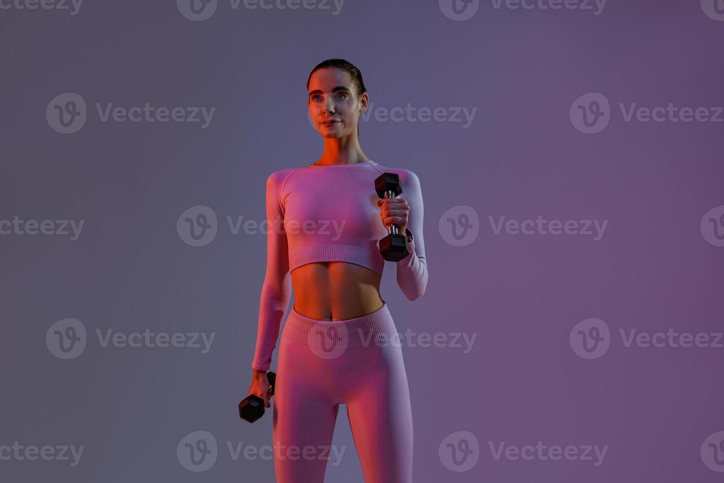 Pretty fitness woman doing exercises with dumbbells on studio background. Strength and motivation photo