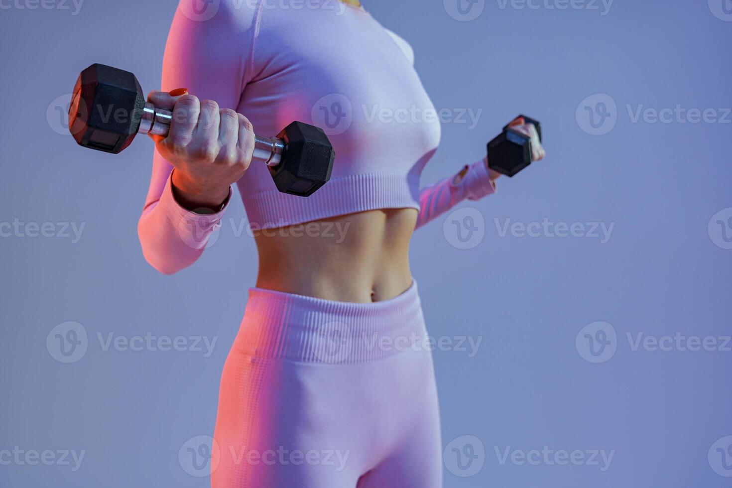 Close up of woman doing exercises with dumbbells on studio background. Strength and motivation photo
