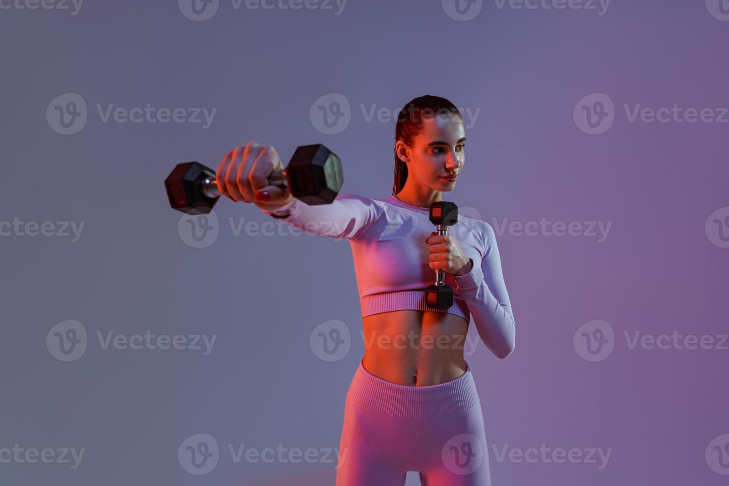 Fitness woman doing exercises with dumbbells on studio background. Strength and motivation photo