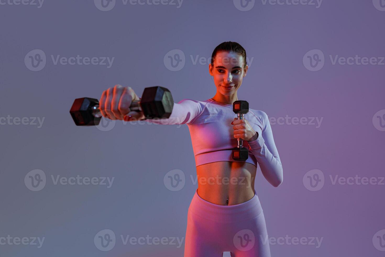 Pretty fitness woman doing exercises with dumbbells on studio background. Strength and motivation photo
