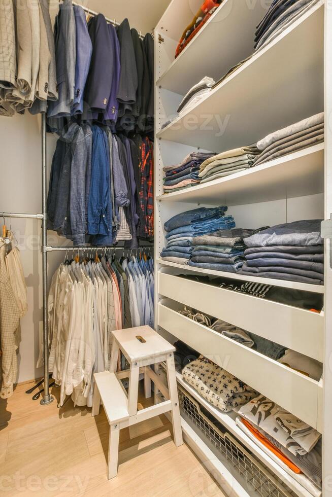 A walk in closet with clothes and shoes photo