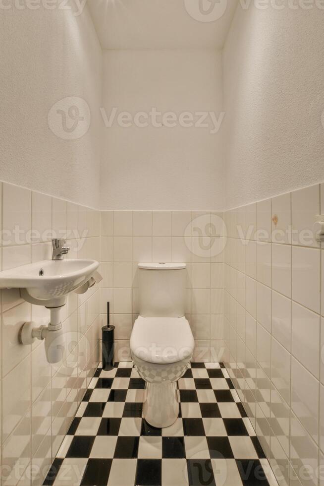 A white toilet sitting in a bathroom with a black and white checkered floor photo