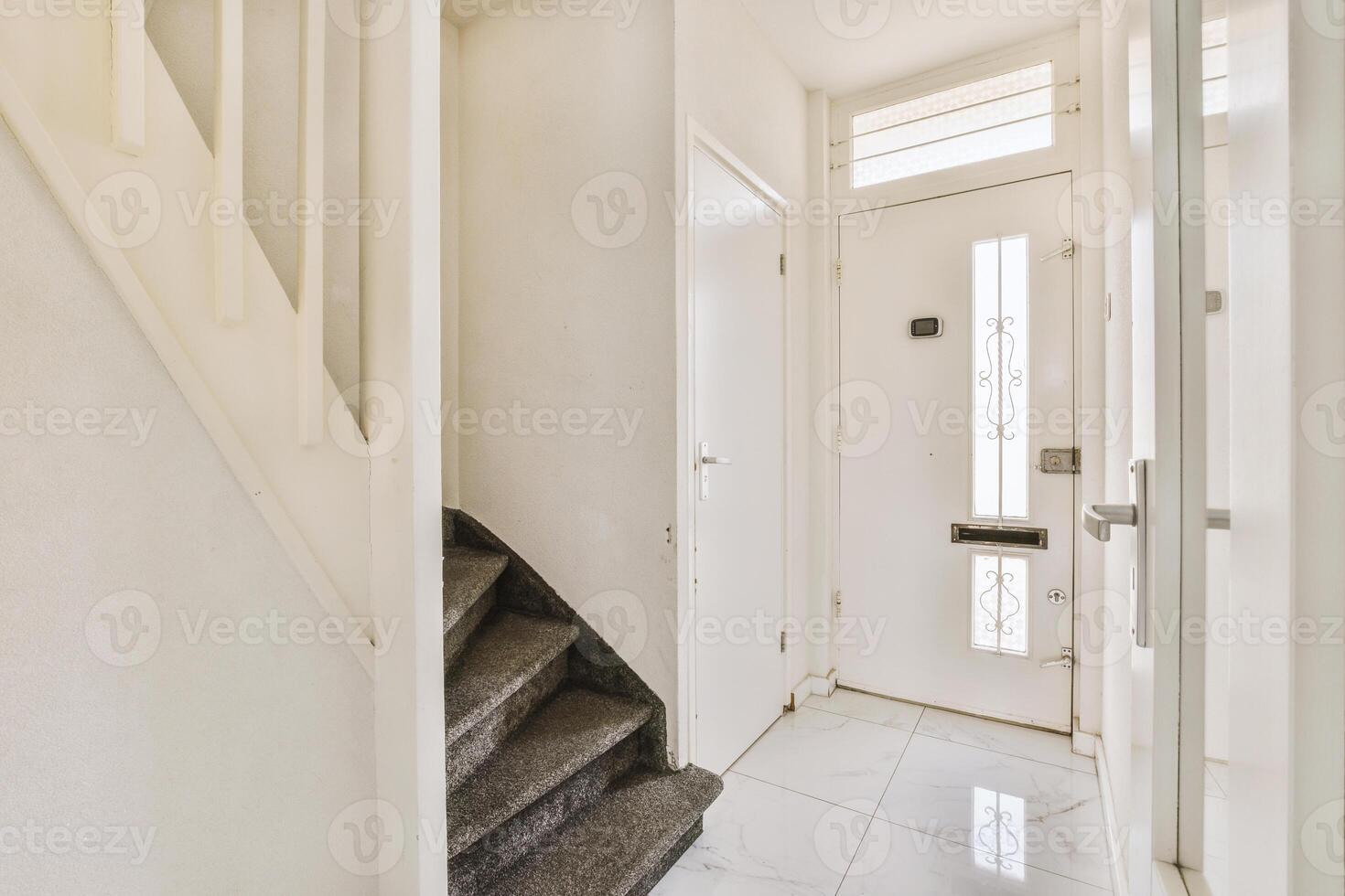 A hallway with a white door and stairs photo