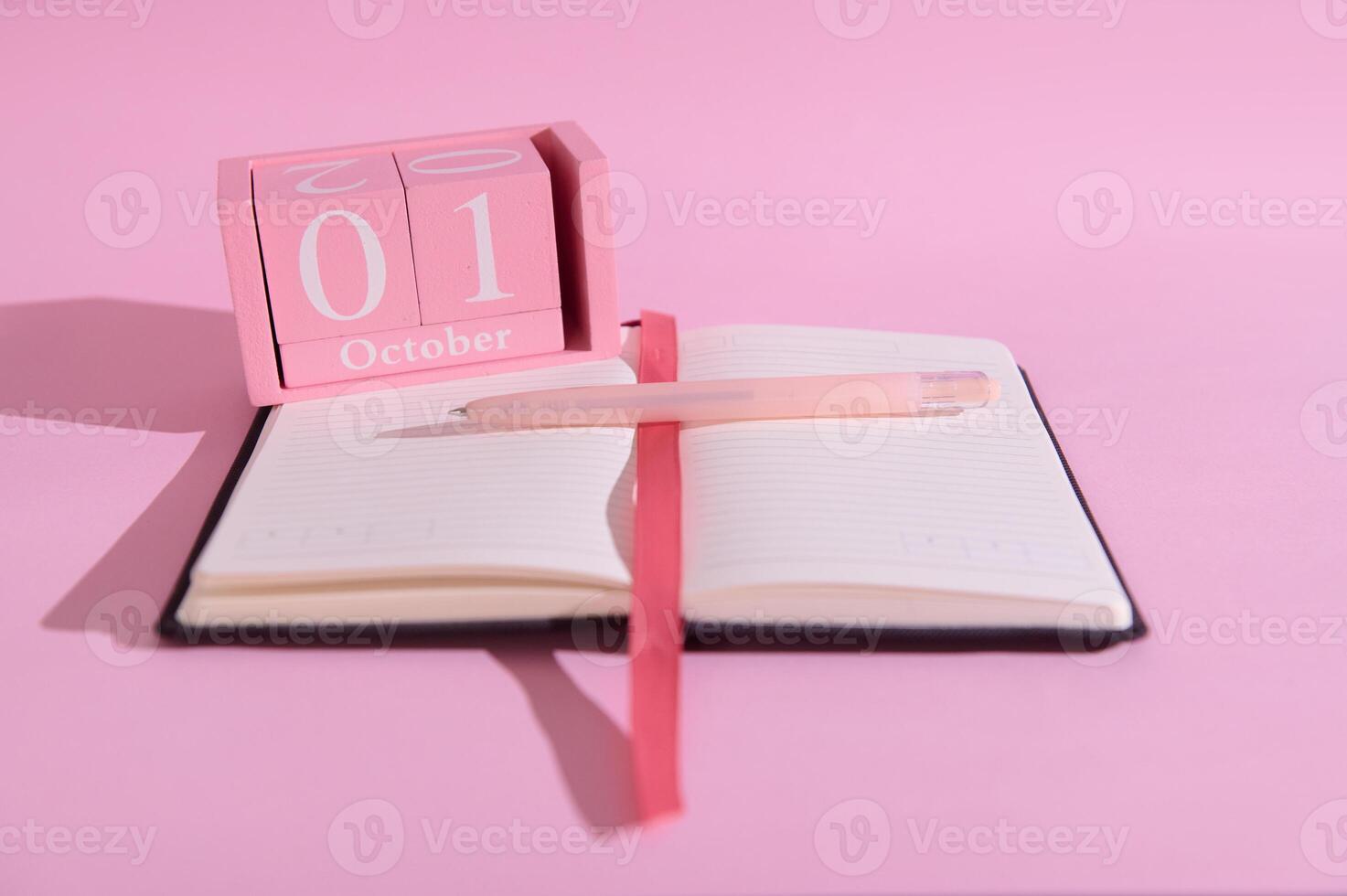 Pink October calendar and notebook with pen on pink background emphasizing planning and organization photo