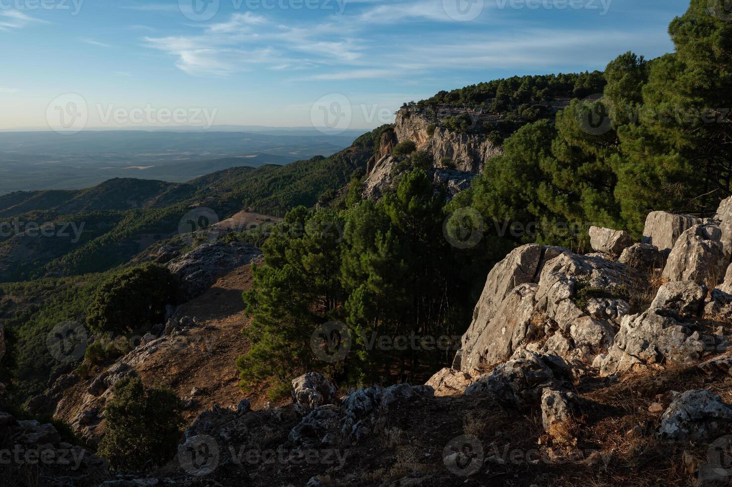 Scenic view of a rugged mountain landscape with lush green forests under a clear blue sky photo