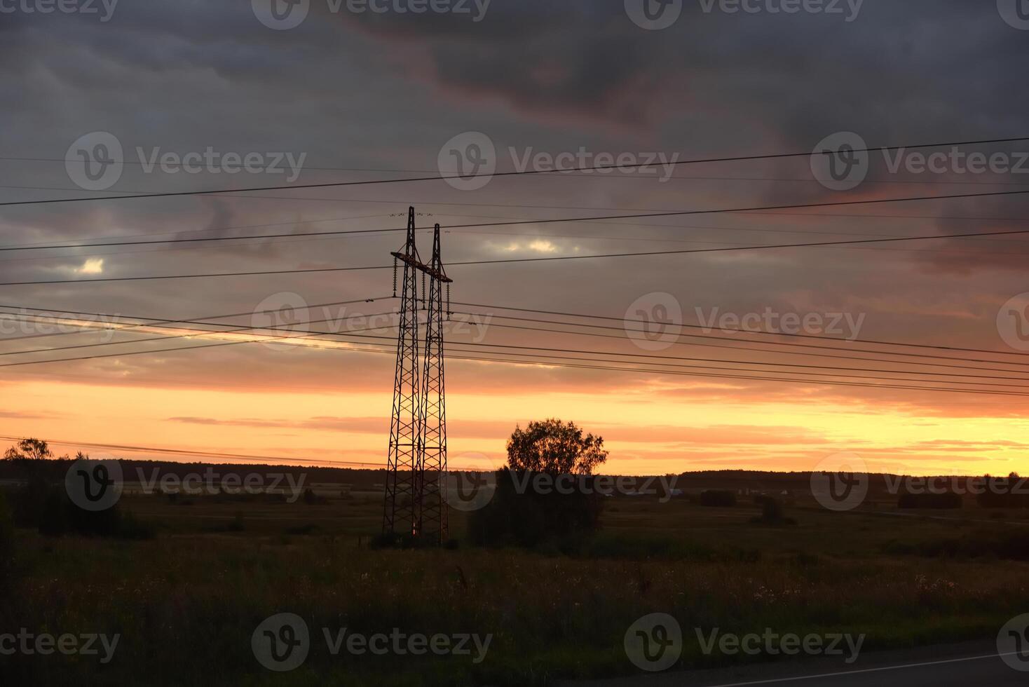 The evening landscape and the setting sun. High-voltage wires and an asphalt road in the evening. photo