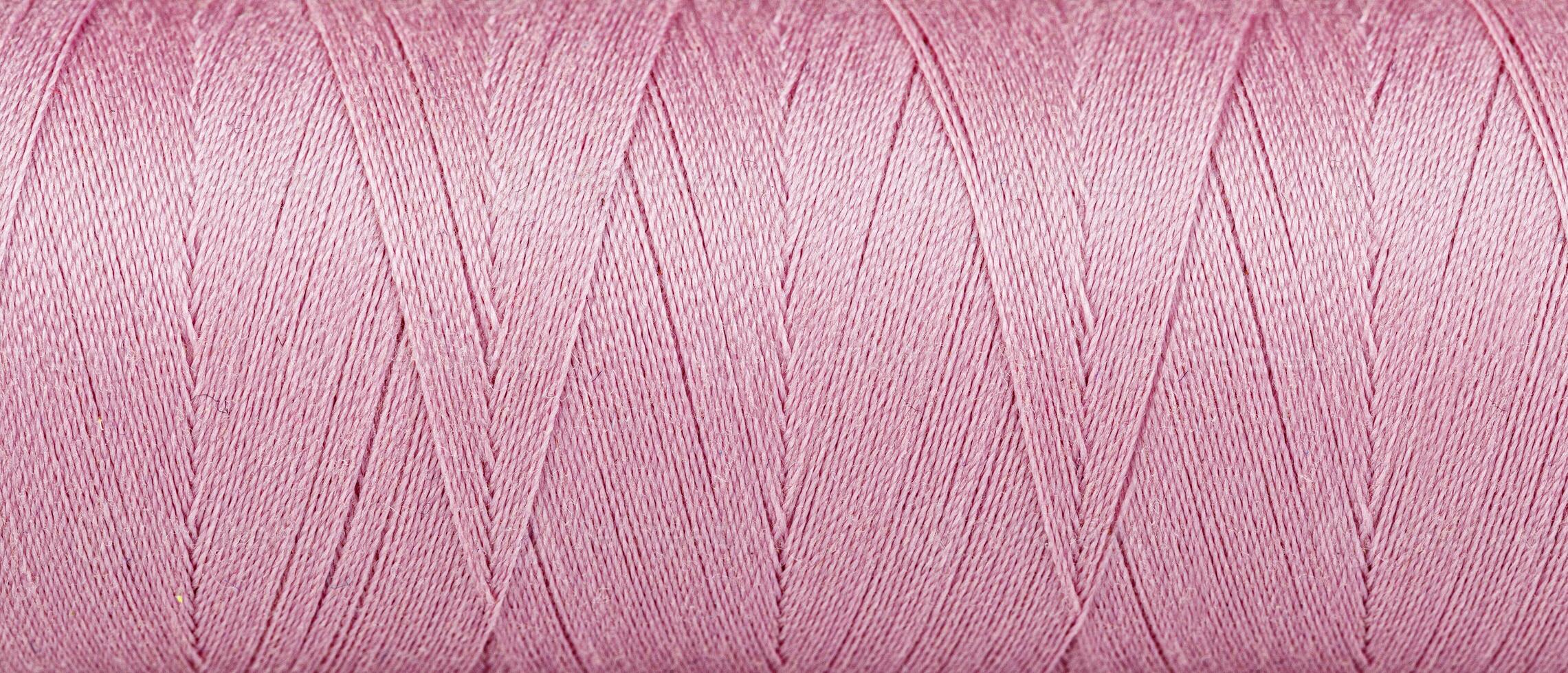 Texture of threads in a spool of pink color on a white background photo