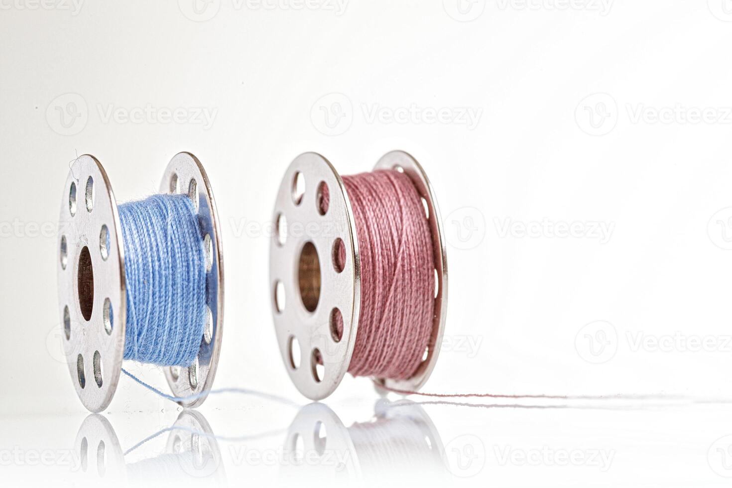 spools of blue and pink thread on a white background photo