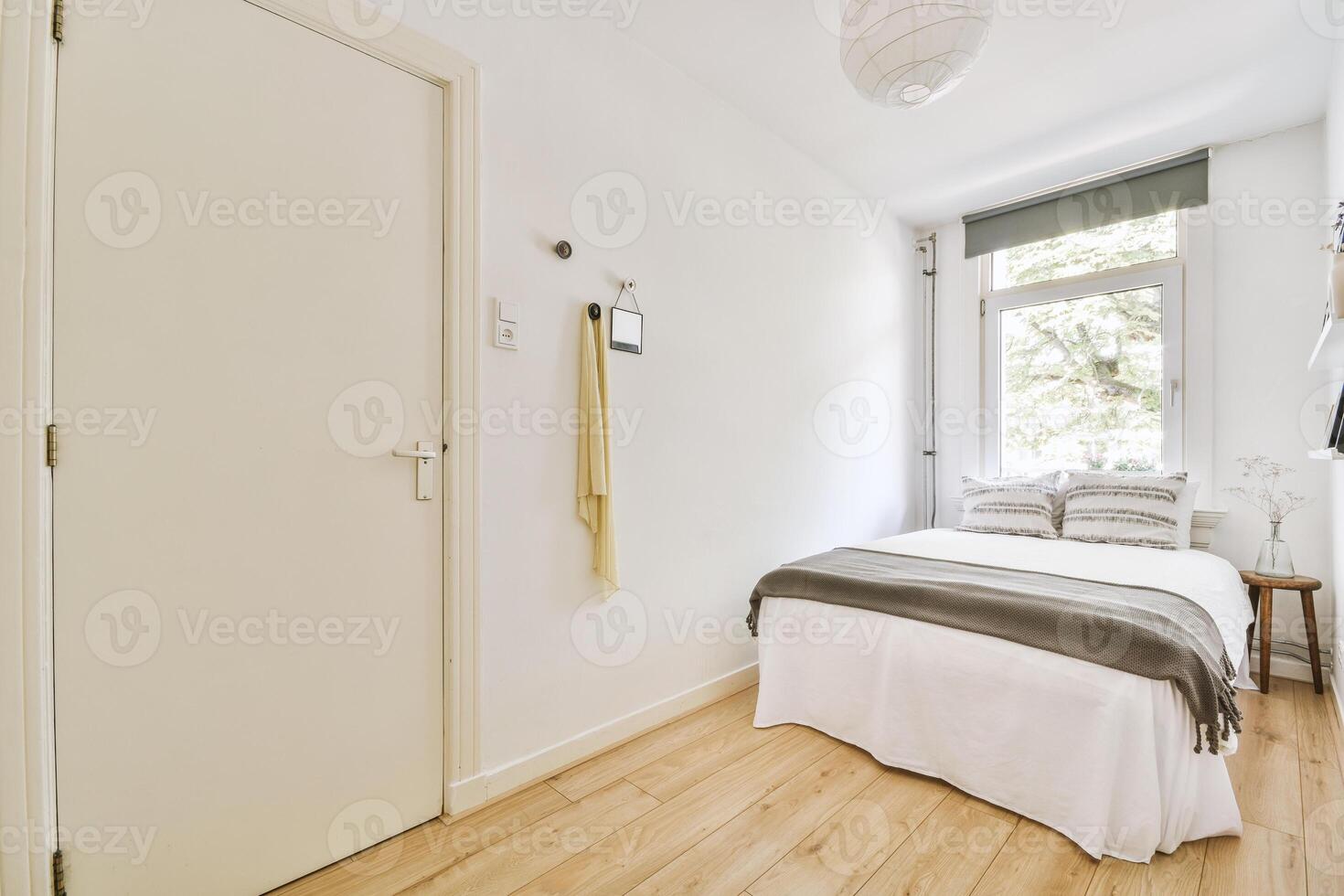 A small bedroom with a bed and a wooden floor photo