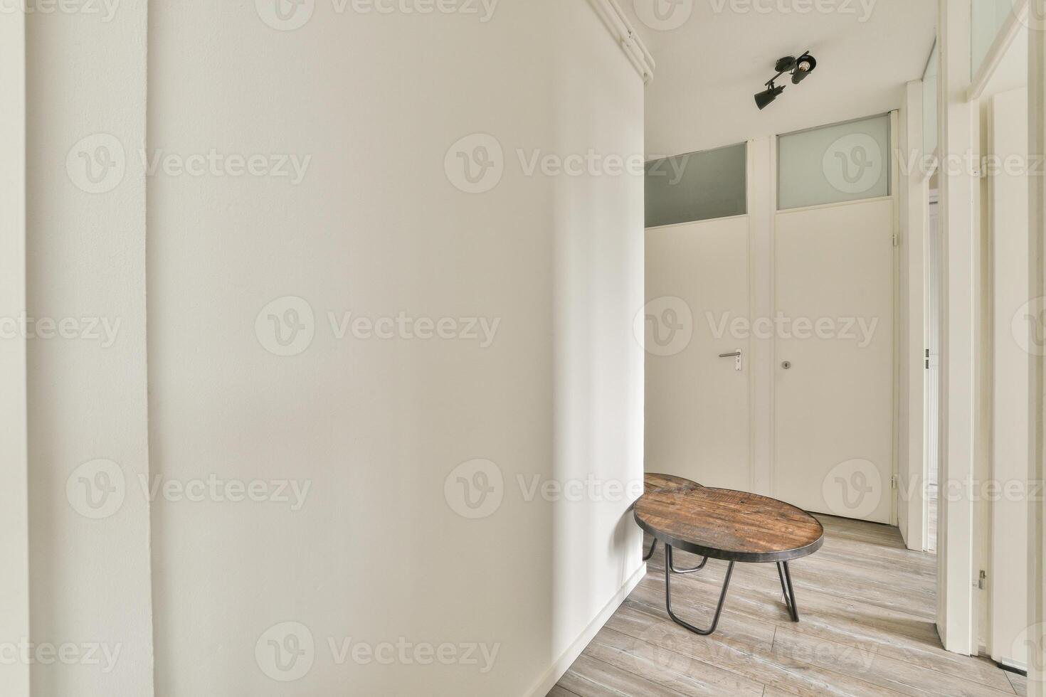 A white hallway with a wooden table and a chair photo