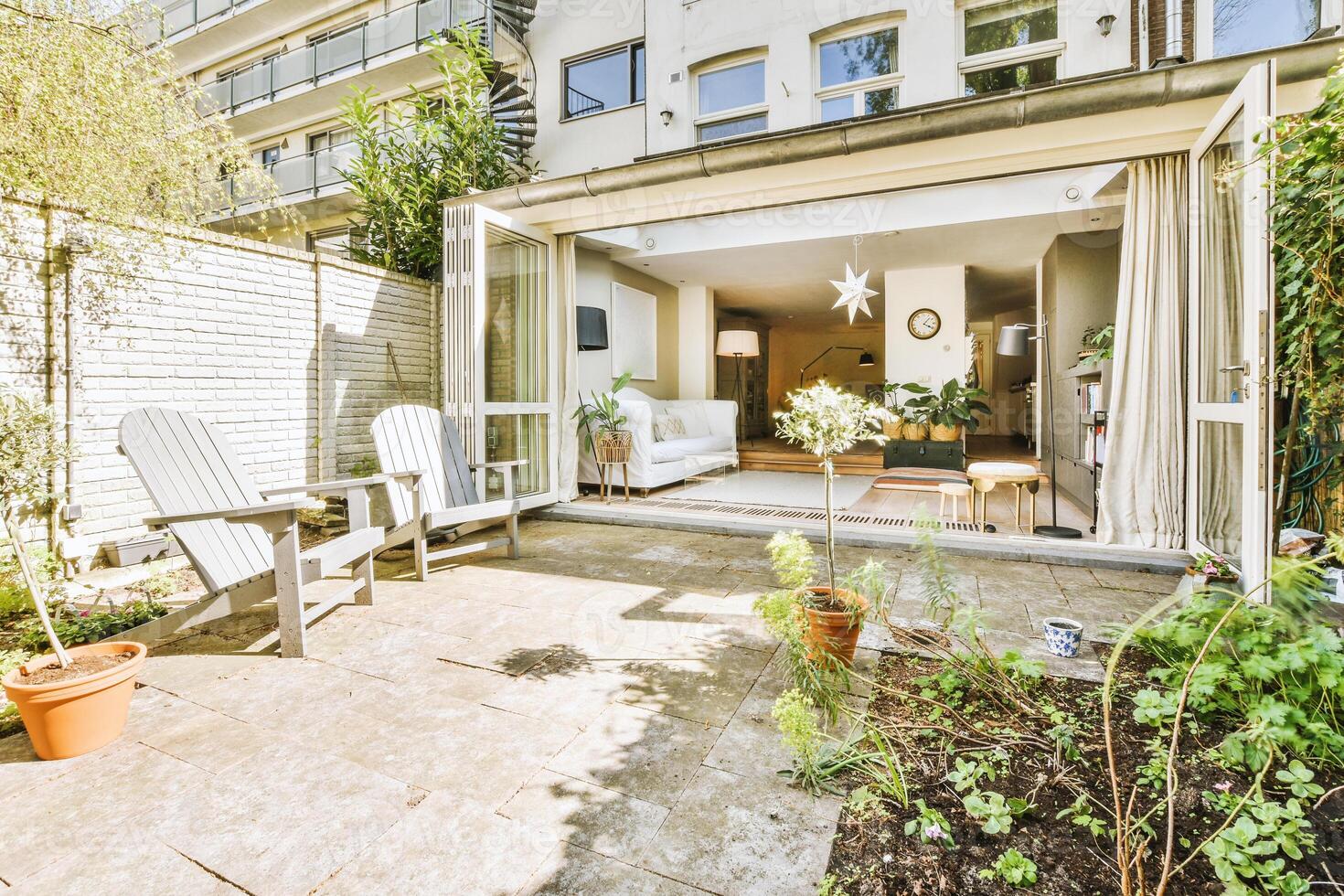 A patio area with chairs and a table in front of a building photo