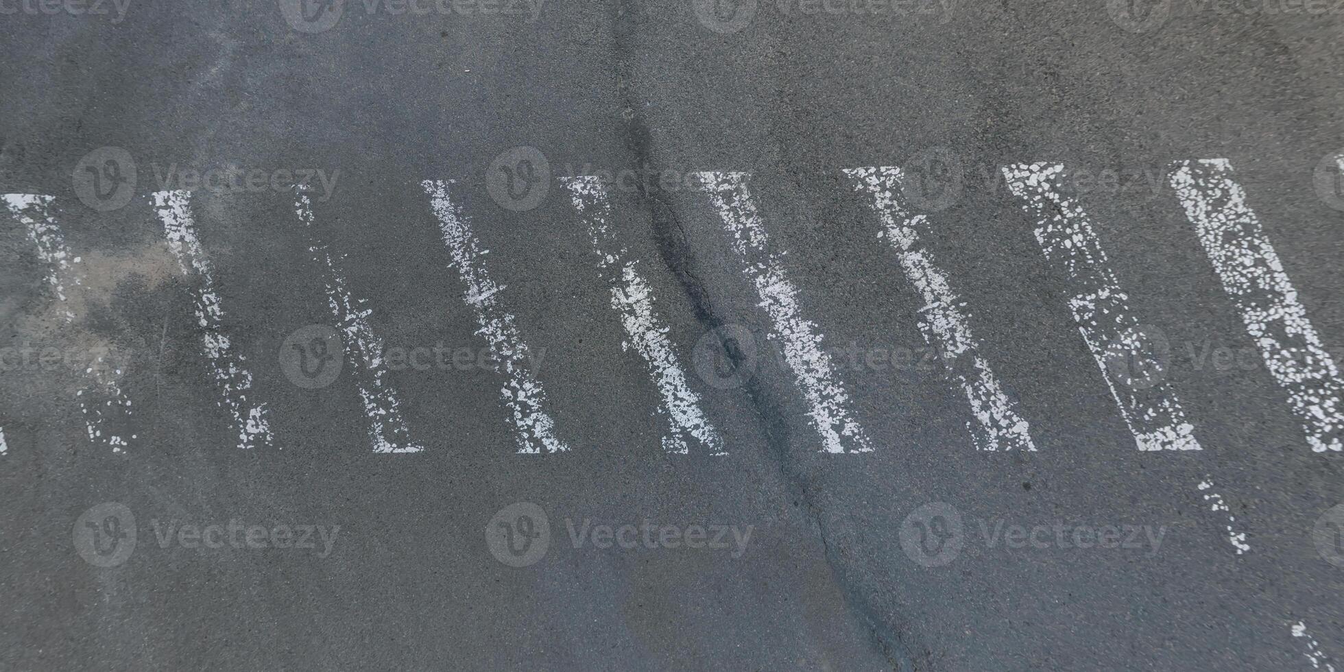 view from above on texture of asphalt road with old white stripes worn out photo