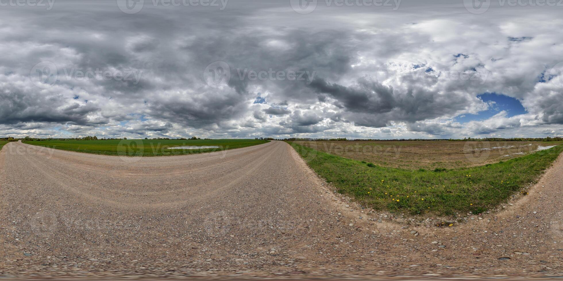 hdri 360 panorama on wet gravel road among fields in spring nasty day with storm clouds before sunset in equirectangular full seamless spherical projection, for VR AR virtual reality content photo