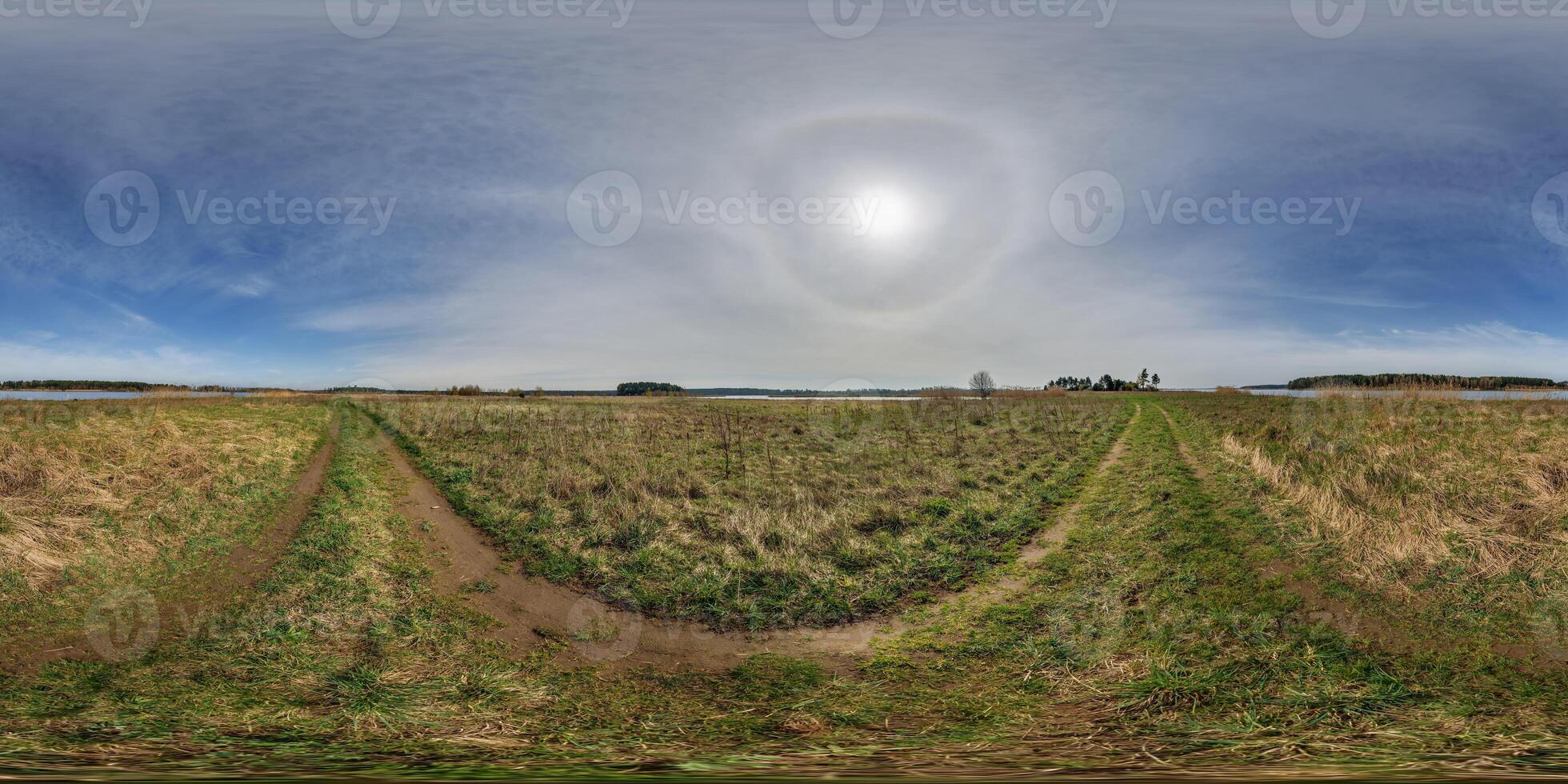 full seamless spherical hdri panorama 360 degrees angle view among fields in early spring day with sun on clear sky with halo in equirectangular projection, ready for VR AR content photo