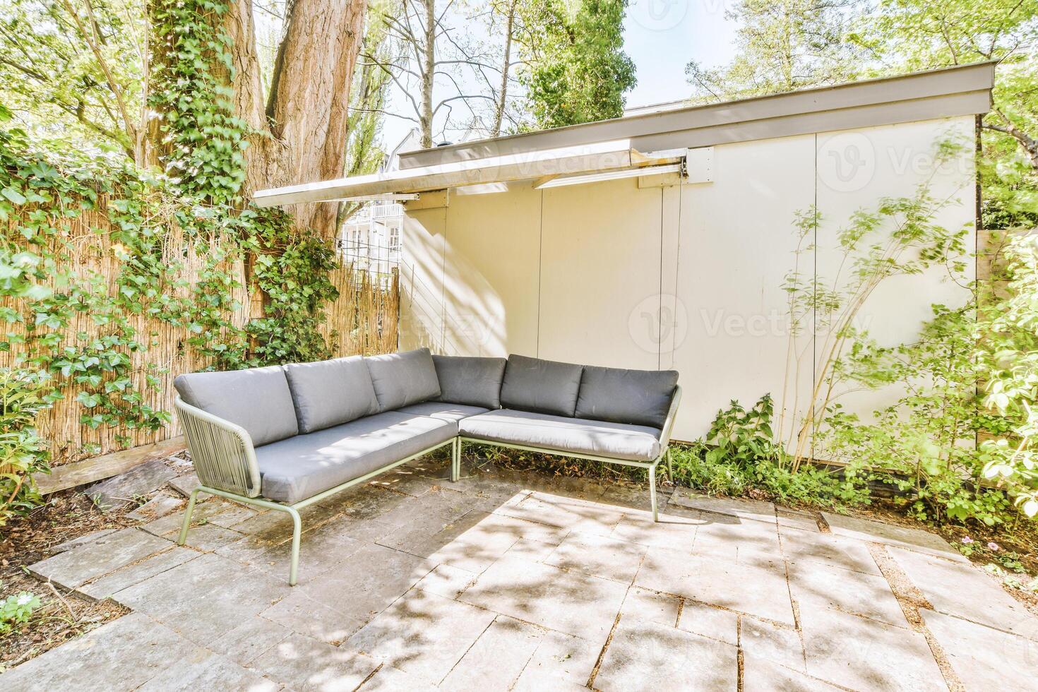 A patio with a couch and a small shed photo