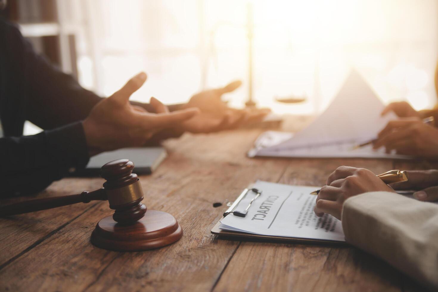 Business and lawyers discussing contract papers with brass scale on desk in office. Law, legal services, advice, justice and law concept picture with film grain effect photo