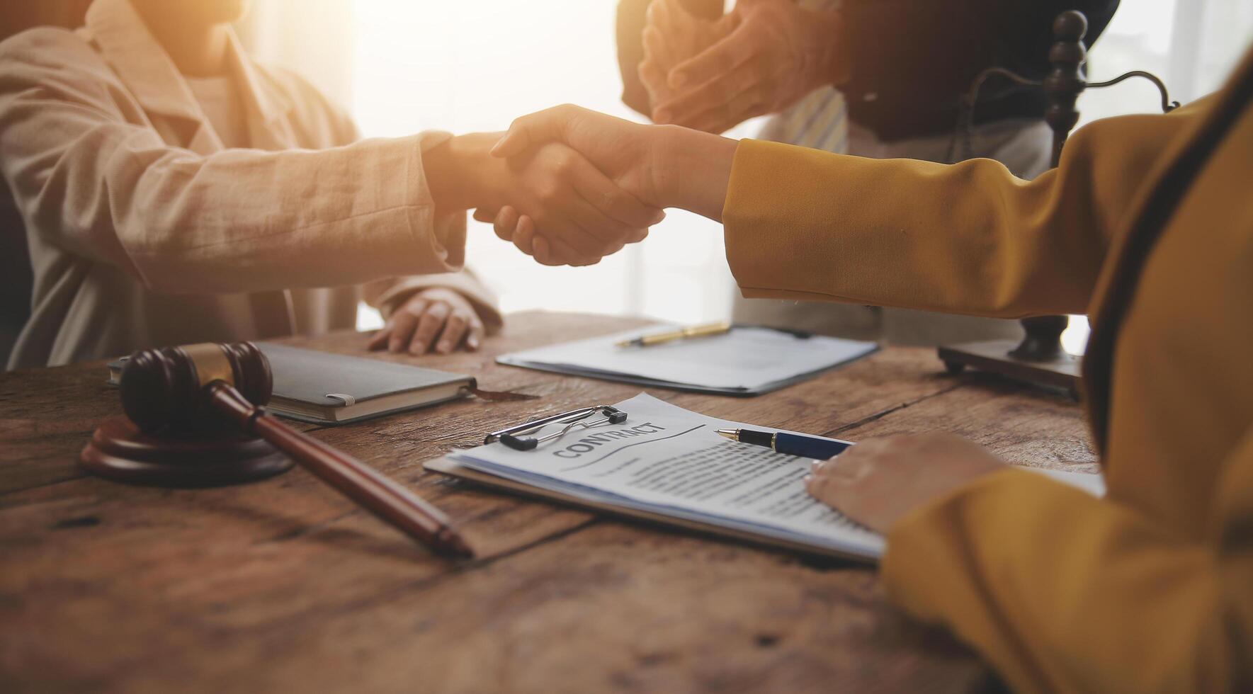 Lawyer shaking hands with a client making about documents, contracts, agreements, cooperation agreements with a female client at the lawyer's desk and a hammer at the table. photo