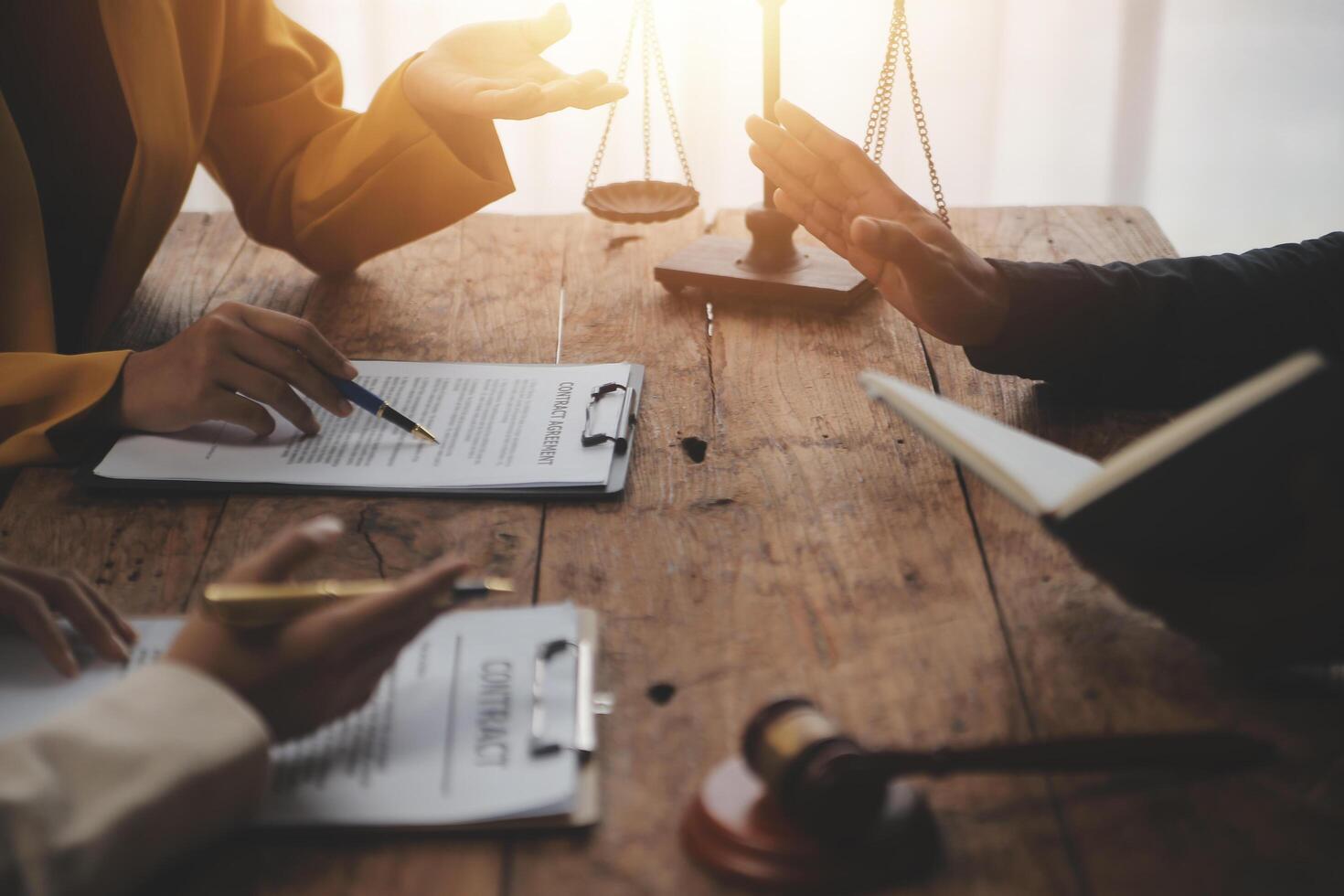 Business and lawyers discussing contract papers with brass scale on desk in office. Law, legal services, advice, justice and law concept picture with film grain effect photo