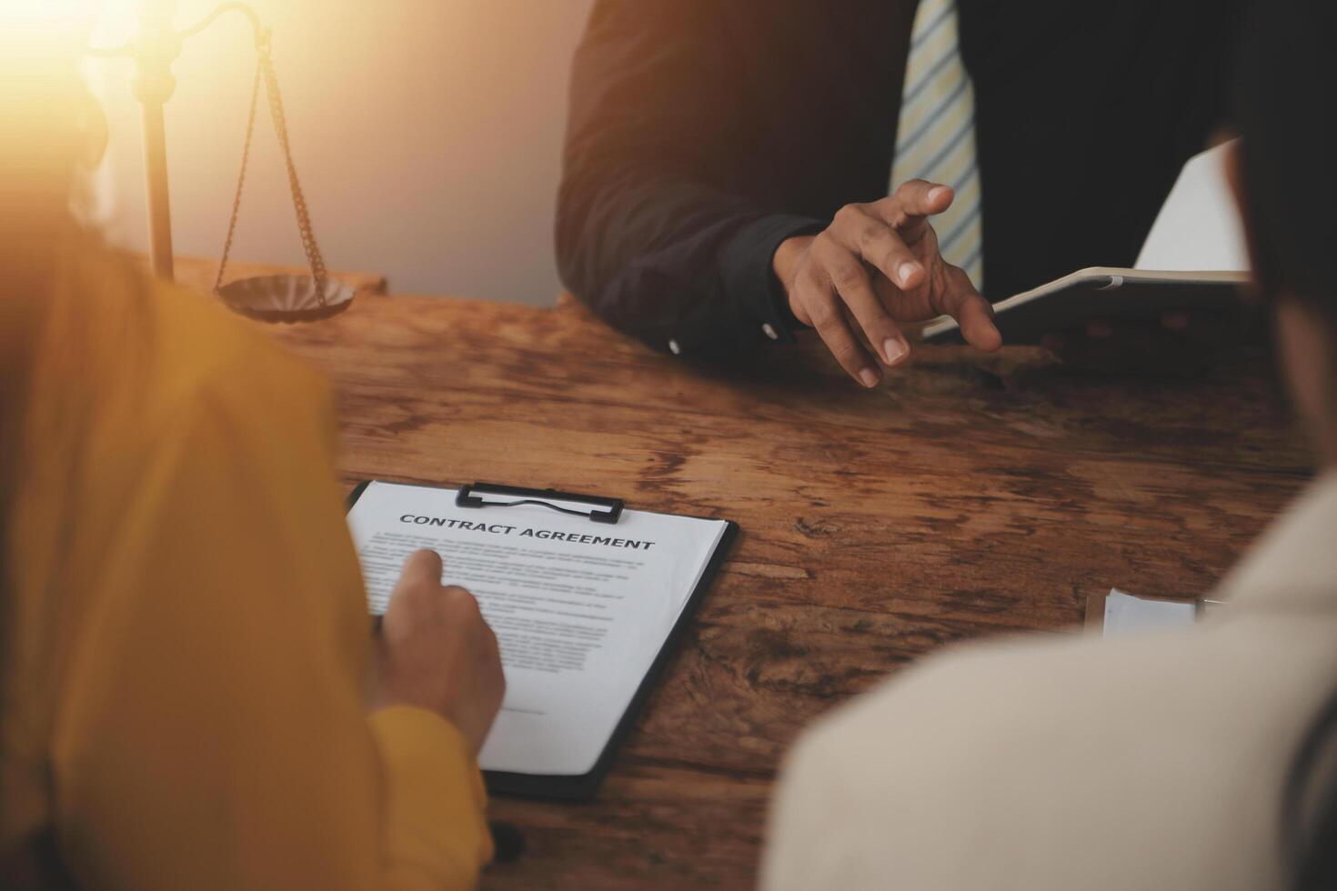 Business and lawyers discussing contract papers with brass scale on desk in office. Law, legal services, advice, justice and law concept picture with film grain effect photo