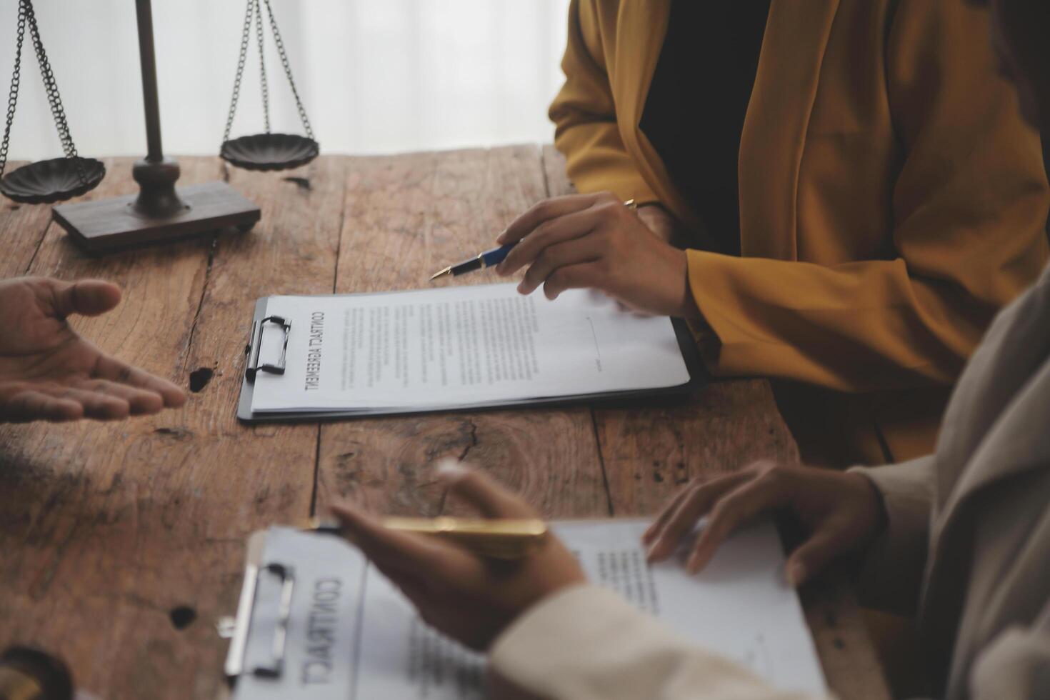 Business and lawyers discussing contract papers with brass scale on desk in office. Law, legal services, advice, justice and law concept picture with film grain effect photo