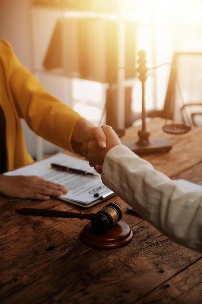 Lawyer shaking hands with a client making about documents, contracts, agreements, cooperation agreements with a female client at the lawyer's desk and a hammer at the table. photo