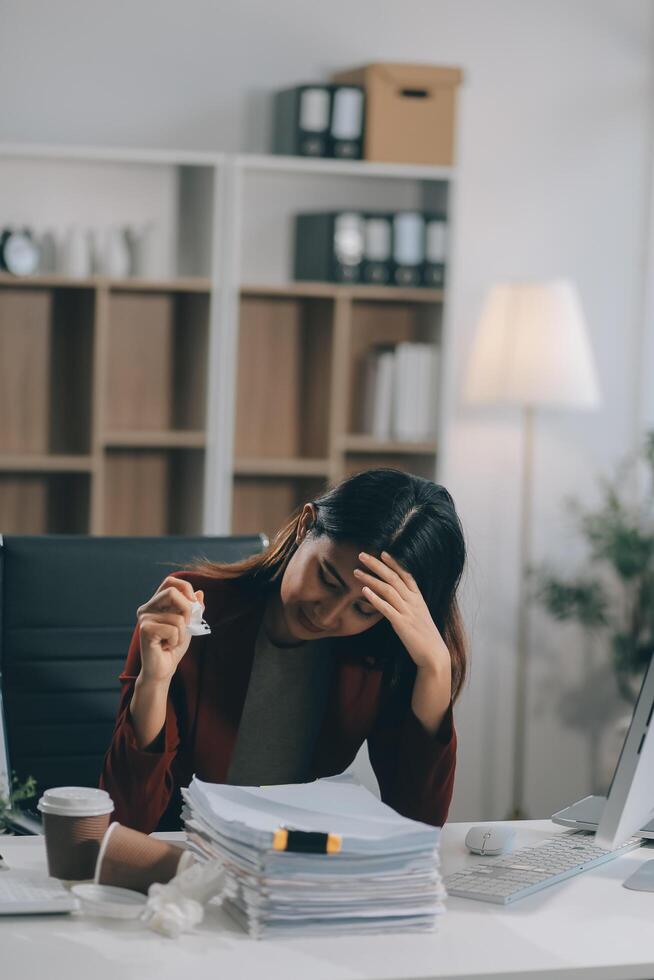 Young asian business woman with tired eyes and headache photo