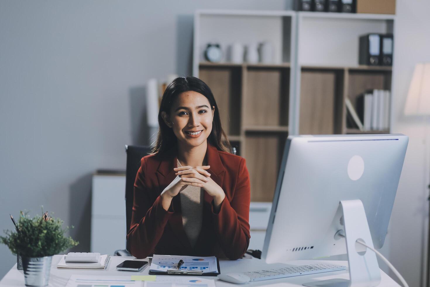 Cheerful business lady working on laptop in office, Asian happy beautiful businesswoman in formal suit work in workplace. Attractive female employee office worker smile. photo