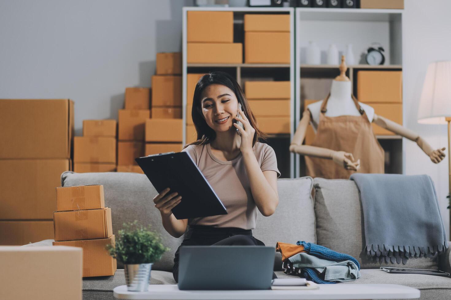 Asian SME business women use laptop computer checking customer order online shipping boxes at home. Starting Small business entrepreneur SME freelance. Online business, Work at home concept. photo