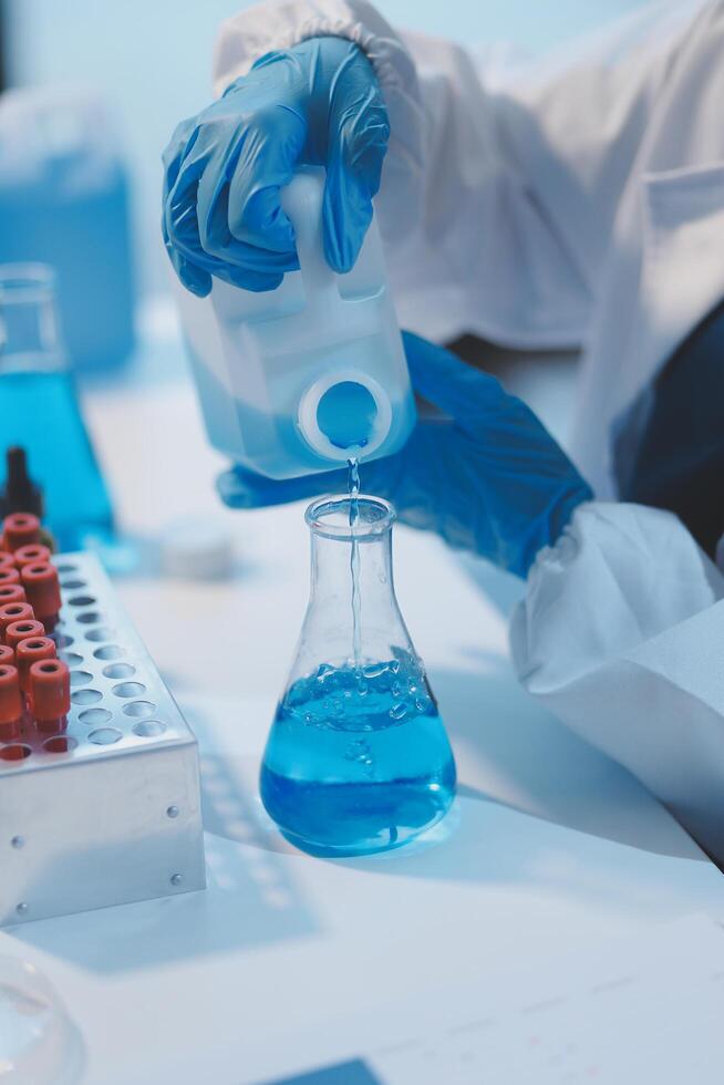Group of dedicated scientist conduct chemical experiment in medical laboratory, carefully drop precise amount of liquid from pipette into test tube for vaccine drug or antibiotic development. Neoteric photo