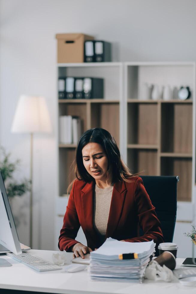 Young asian business woman with tired eyes and headache photo