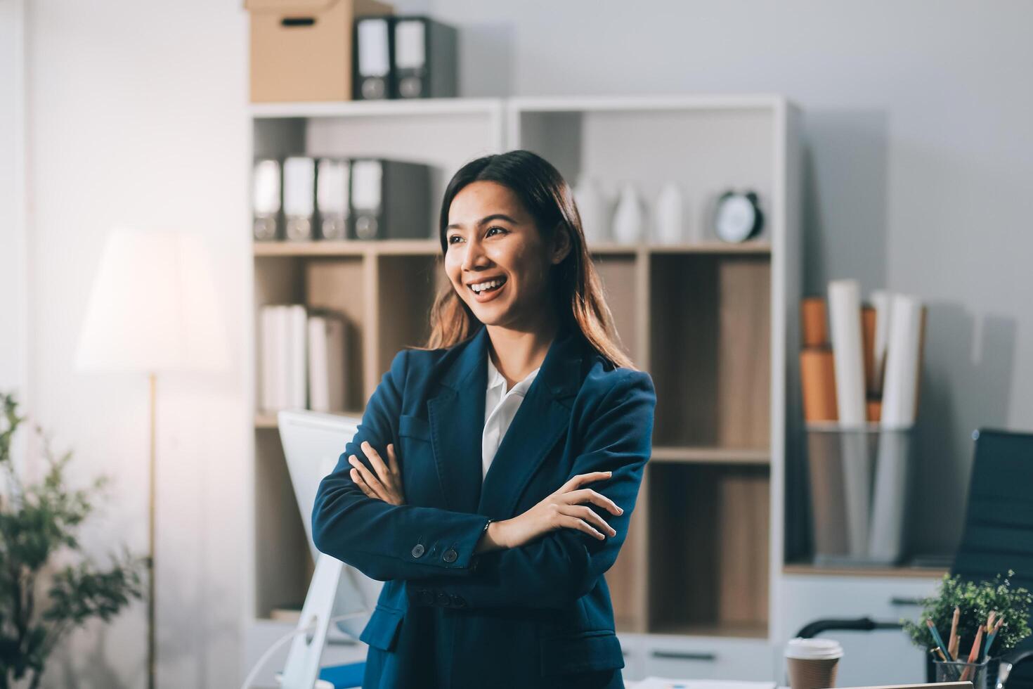 Portrait of Happy young Asian businesswoman looking at camera,arms crossed folded.Smiling woman executive manager,secretary offering professional business services standing in office. photo