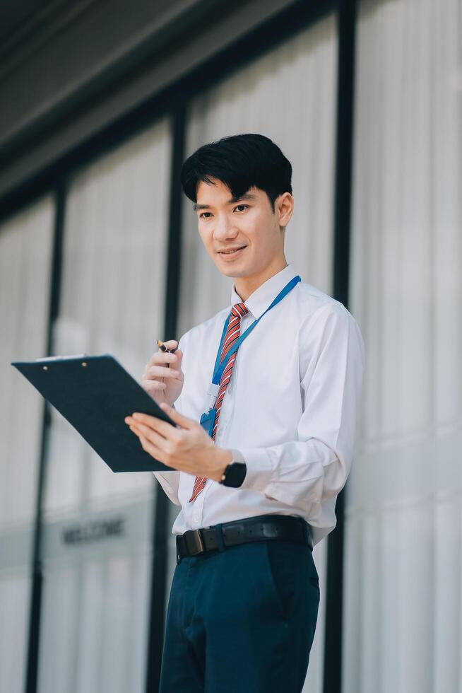 Serious businessman looking at paper documents in front of office building. Focused male manager checking reports before work while standing outdoors. photo