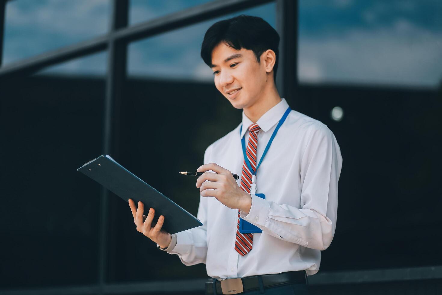 Serious businessman looking at paper documents in front of office building. Focused male manager checking reports before work while standing outdoors. photo