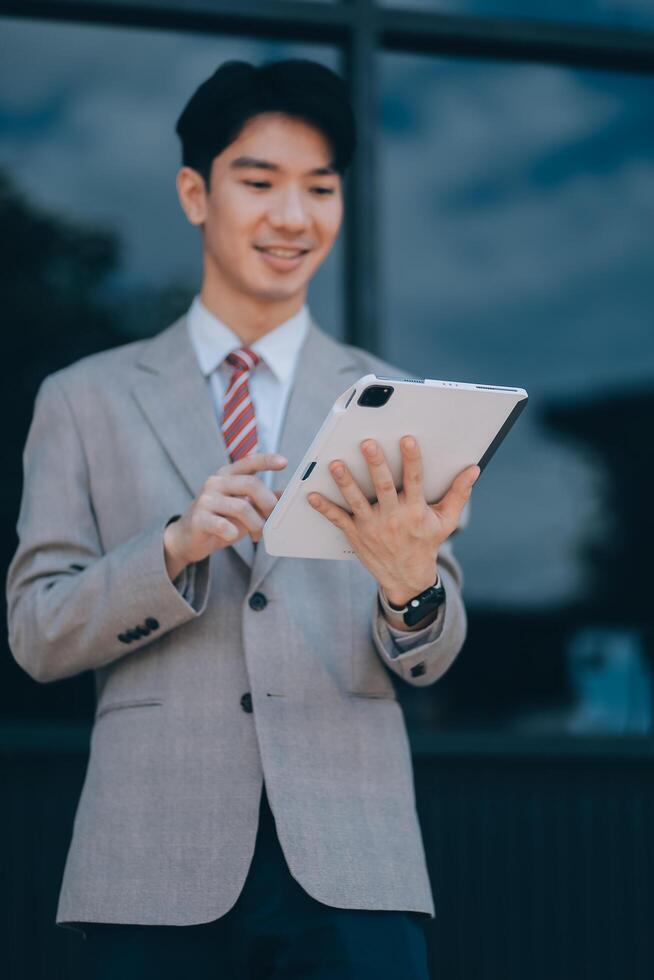 Serious businessman looking at paper documents in front of office building. Focused male manager checking reports before work while standing outdoors. photo