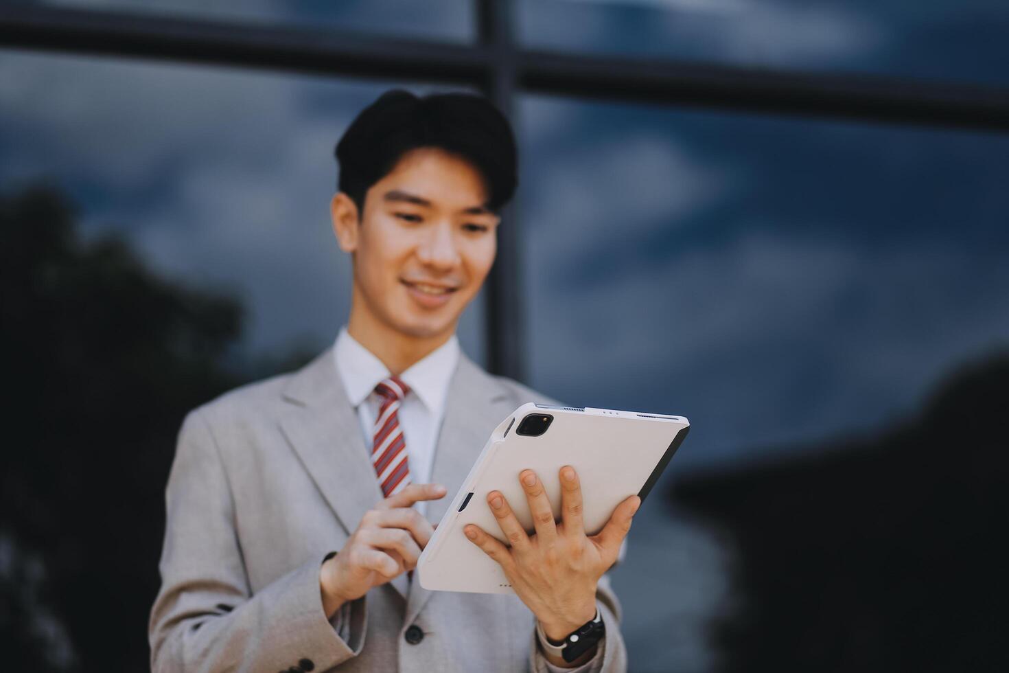 Serious businessman looking at paper documents in front of office building. Focused male manager checking reports before work while standing outdoors. photo