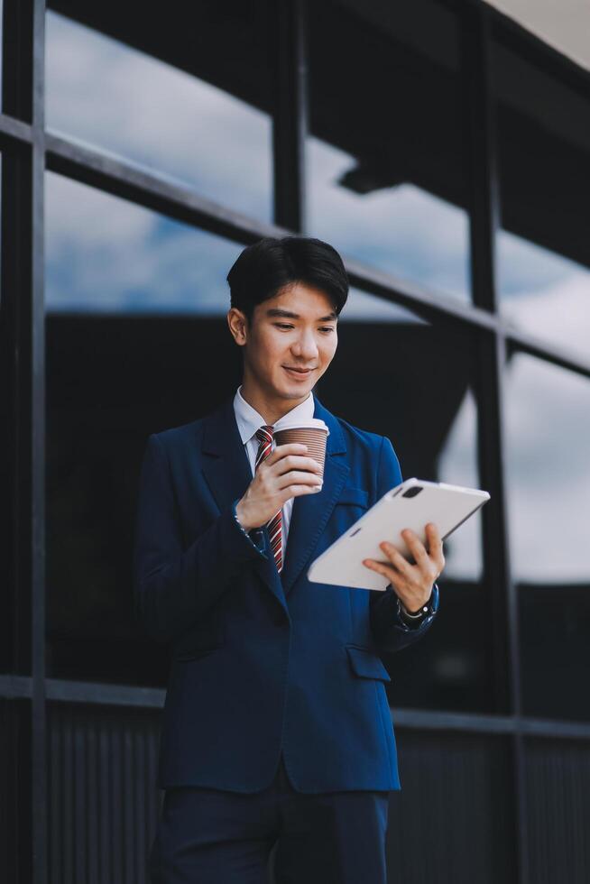 Businessman using tablet and enjoying in coffee break in front of the the corporation. Business, lifestyle concept photo