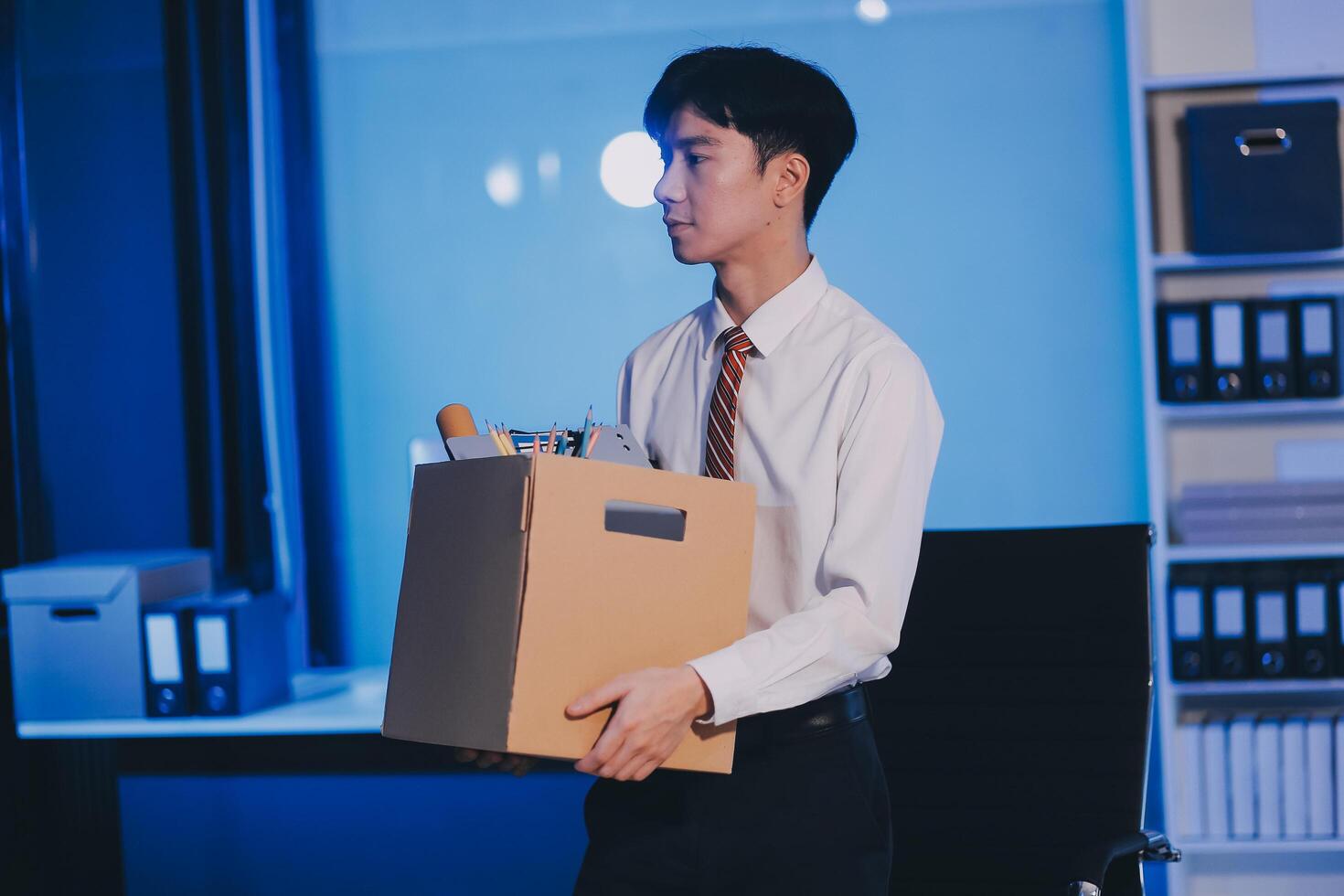 lose job, Your fired. Unhappy business man with surgical medical mask going out with cardboard, looking at camera and feeling looser. indoor shot. business, working and health care concept. photo