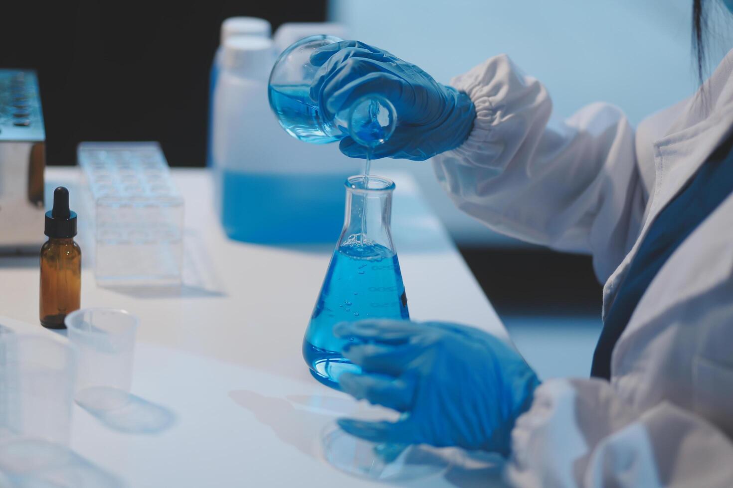 Group of dedicated scientist conduct chemical experiment in medical laboratory, carefully drop precise amount of liquid from pipette into test tube for vaccine drug or antibiotic development. Neoteric photo