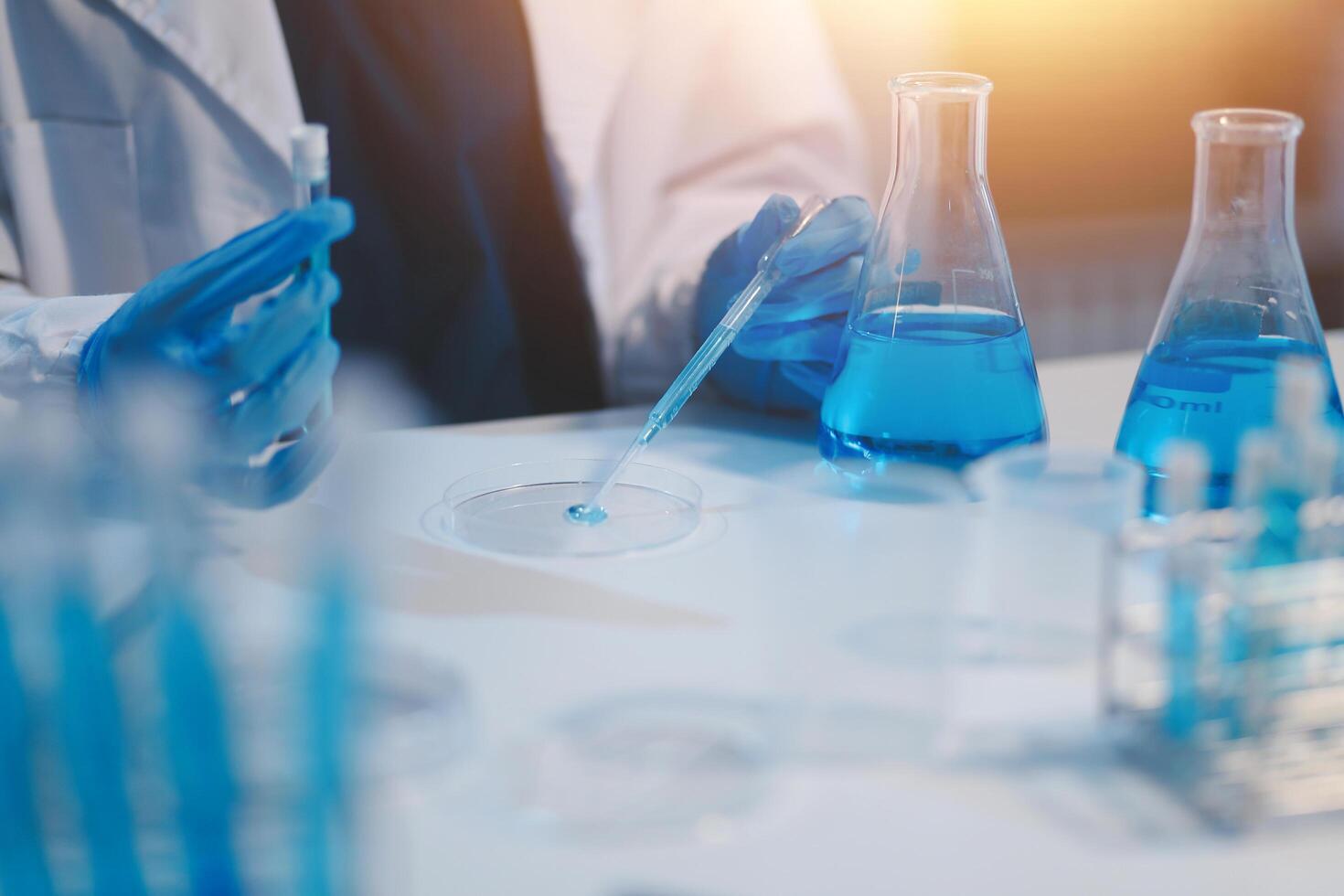 Group of dedicated scientist conduct chemical experiment in medical laboratory, carefully drop precise amount of liquid from pipette into test tube for vaccine drug or antibiotic development. Neoteric photo