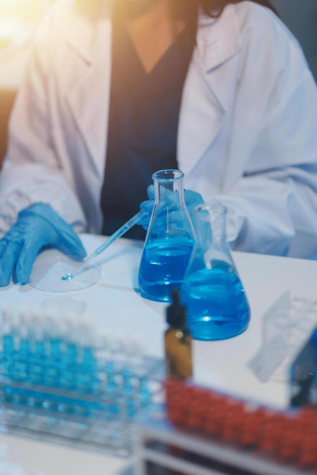 Group of dedicated scientist conduct chemical experiment in medical laboratory, carefully drop precise amount of liquid from pipette into test tube for vaccine drug or antibiotic development. Neoteric photo