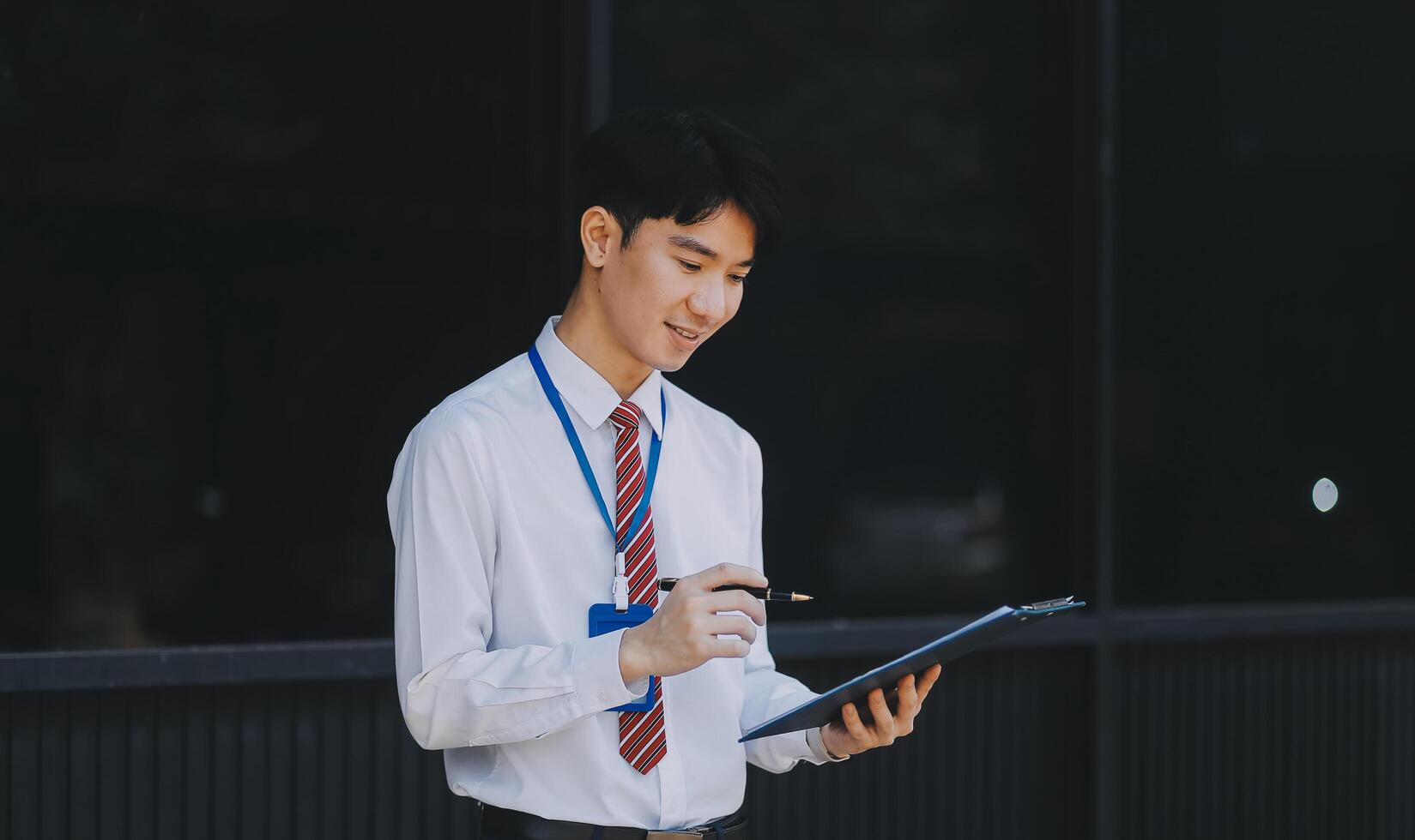 Serious businessman looking at paper documents in front of office building. Focused male manager checking reports before work while standing outdoors. photo