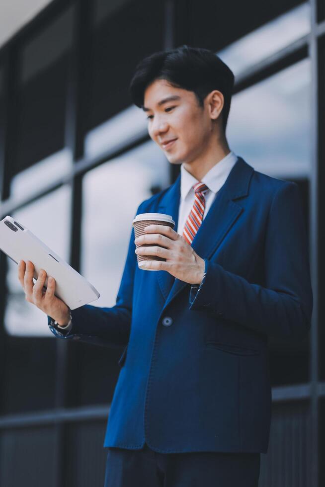 Businessman using tablet and enjoying in coffee break in front of the the corporation. Business, lifestyle concept photo