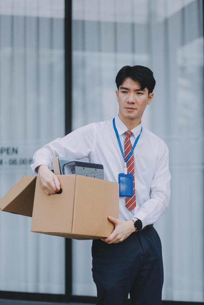 Sadness depressed Businessman with box cardboard packing personal items after losing jobs. Failure businessman sitting at stair front of building. Your fired Unemployed Jobless People Crisis photo